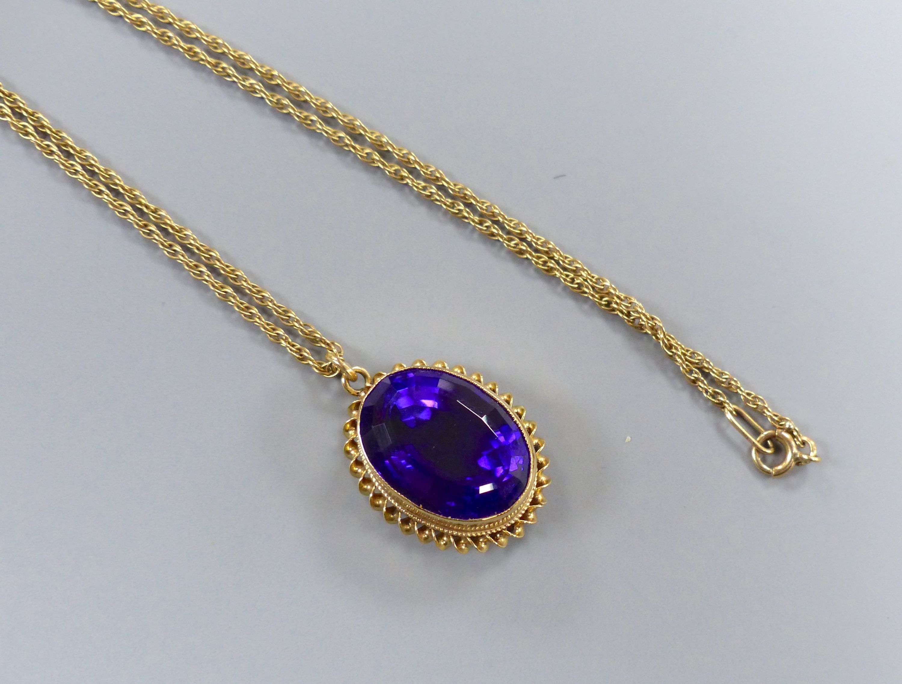 A modern 9ct gold and oval cut amethyst set pendant, 24mm, on a 9ct chain, 46cm,